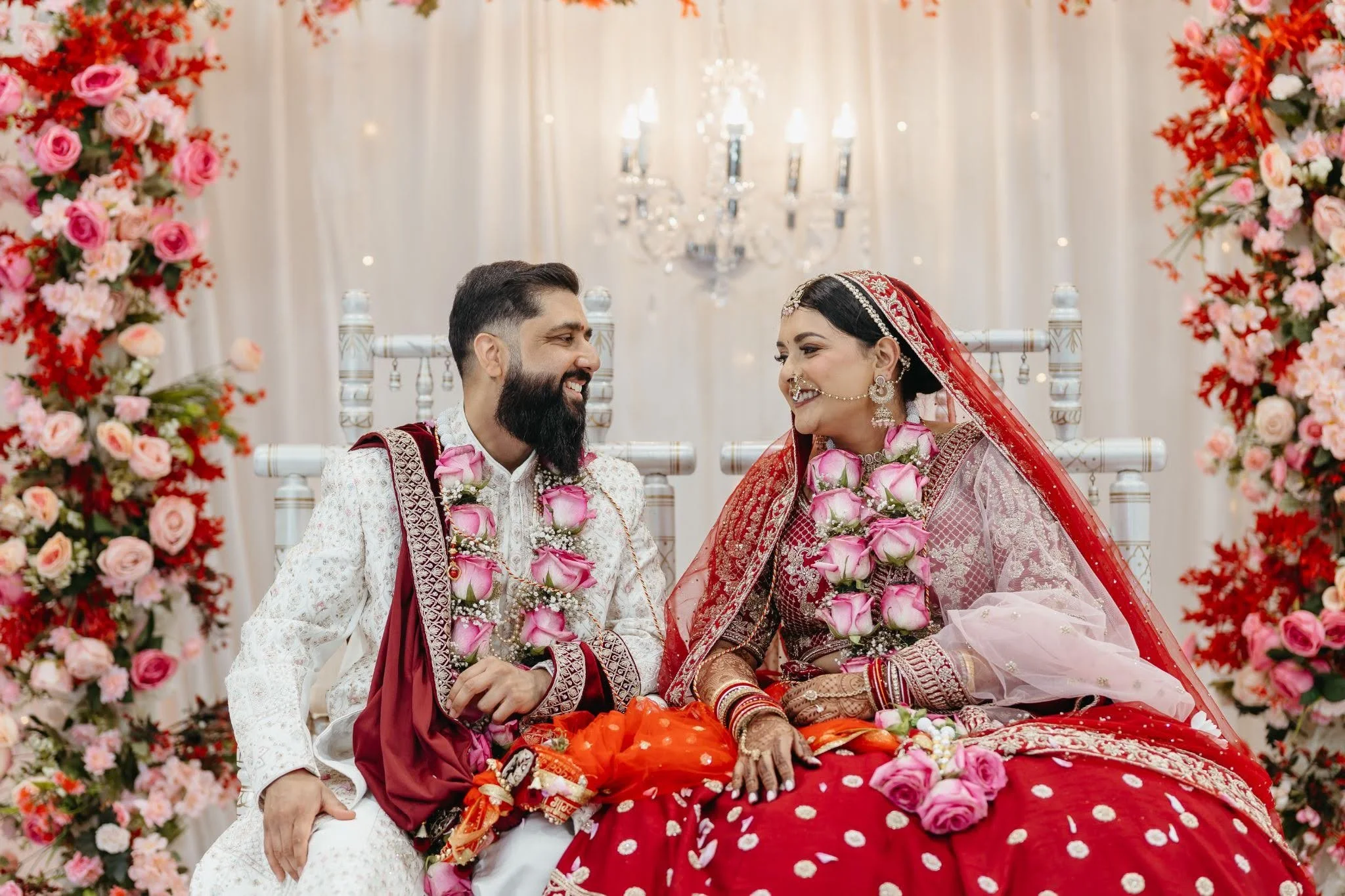 Hindu wedding couple smiling under floral décor.